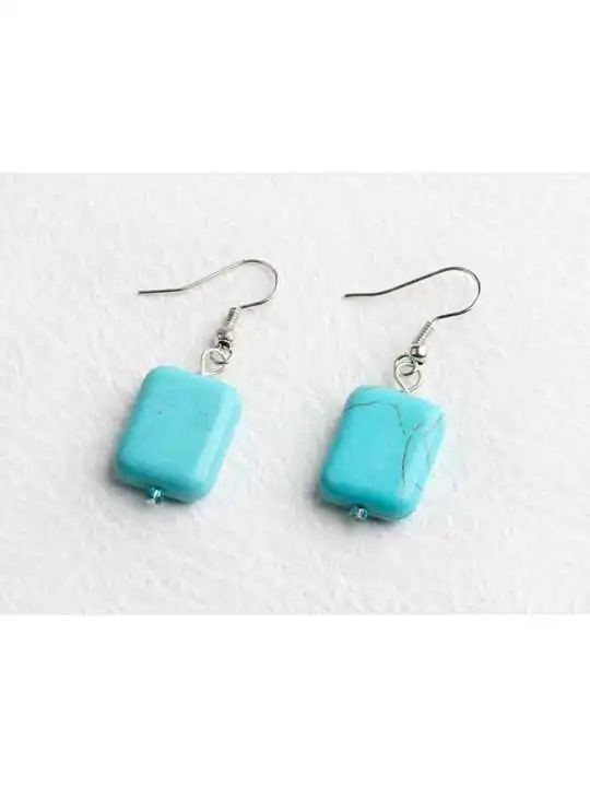 detalle de pendientes con dado howlita color turquesa