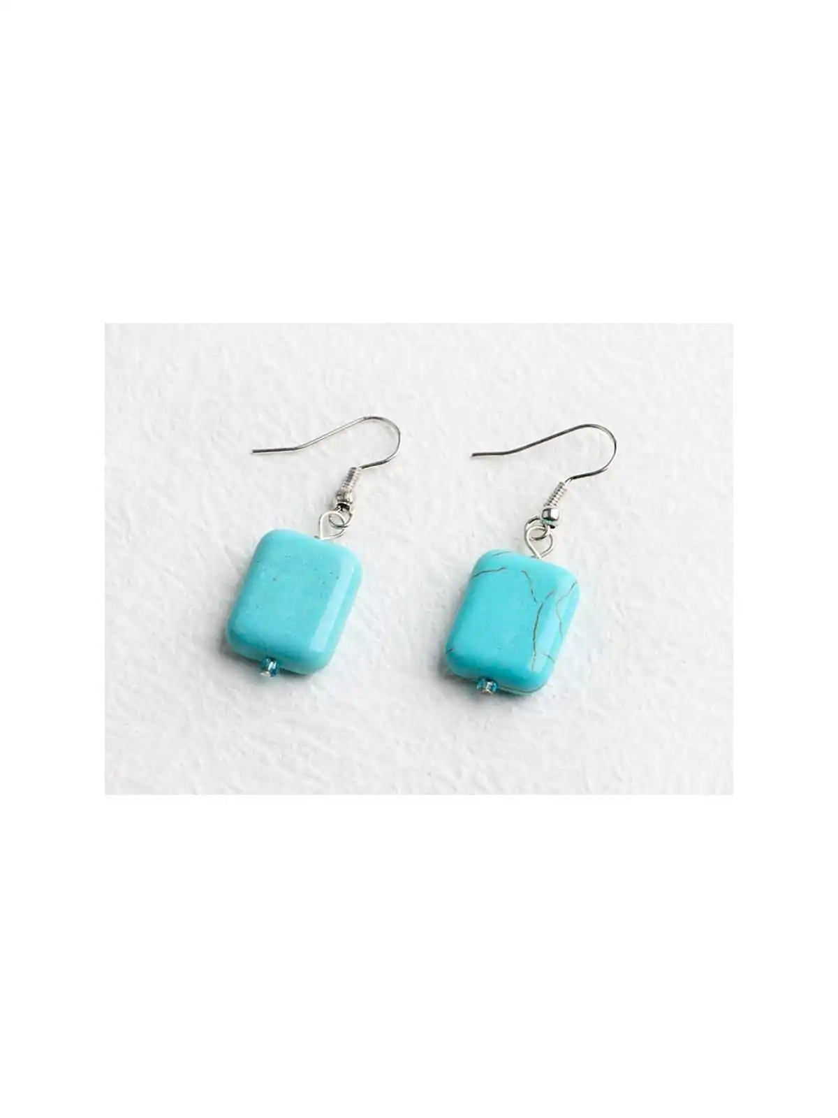 detalle de pendientes con dado howlita color turquesa